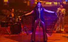 a woman standing in front of a microphone on top of a wooden floor next to other people