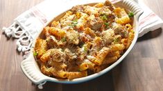 a casserole dish filled with meat and cheese on top of a wooden table