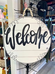 a welcome sign hanging from the side of a store's wall in front of a bookshelf