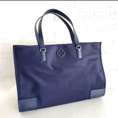 Tory Burch 136144 Ella Nylon Tote Navy Blue Large Shoulder Bag. Nylon Inside Zip And One Slip Pockets Snap Closure, Fabric Lining Handles With 7" (18 Cm) Drop Gold Tone Hardware Approx. Measurement : 16 1/2" (L) X 12" (H) X 5" (W) 42 Cm (L) X 30 Cm (H) X 13 Cm (W) Dust Bag Not Included Blue Nylon Shoulder Bag With Double Handle, Tory Burch Ella Tote, Ella Tote, Tan Handbags, Tory Burch Tote, Rattan Bag, Nylon Tote Bags, Gold Bag, Tory Burch Handbags