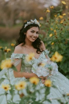 a woman in a green dress standing next to yellow flowers and smiling at the camera