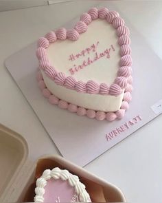 a heart shaped cake sitting on top of a table next to a box of cookies