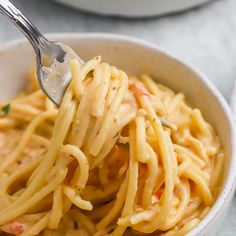 a fork full of pasta in a white bowl