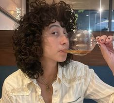 a woman drinking from a wine glass in front of her face