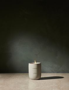 a lit candle sitting on top of a table next to a black wall and floor