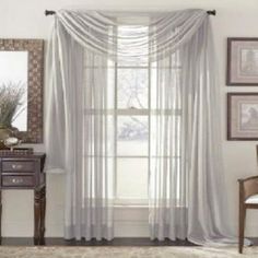 a living room with white curtains and furniture