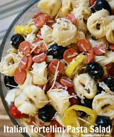 pasta salad with tomatoes, olives, peppers and mozzarella shells in a glass bowl