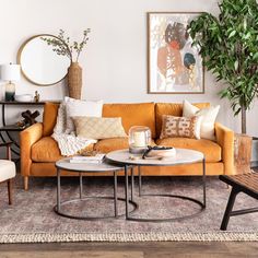 a living room with two couches and a coffee table in front of a potted plant