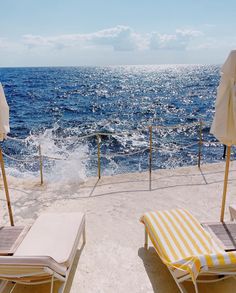 two lounge chairs and an umbrella on the beach