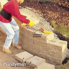 a man standing on top of a cement block wall next to a fire hydrant