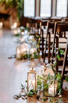 the aisle is lined with candles and greenery as well as small lanterns on them