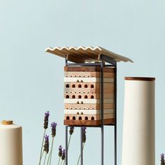 a bird house sitting on top of a wooden table next to two tall white vases