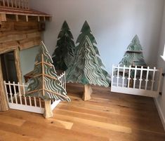 three wooden christmas trees on display in a room with white railings and wood flooring