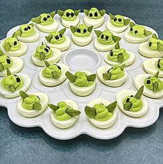 there is a plate with deviled eggs on it and green toppings in the middle