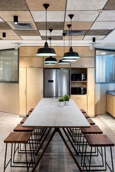 an empty table and benches in a room with wooden cabinets, windows, and lights