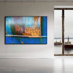 a painting hanging on the wall next to an open door with a ship in the background