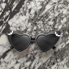 "Attention all Vampires, Witches and Creatures of The Night, we have Goth Retro Heart-Shaped Sunglasses! Embrace the darkness with a hint of retro elegance, as these bewitching shades adorn your eyes with their enchanting design. You can personalize your gothic glasses by selecting a delightfully dark quote of your choice that will appear on the left side arm that is thinly sealed with UV Resin for added protected or if you don't want a quote, you can select \"no quote\". Designed to provide both style and protection, these sunglasses feature high-quality lenses that shield your eyes from harmful UV rays and comes with a Wickedly Divine Shop storage bag. Please note that this is a fragile item and needs to be handled with care. Thanks for your support!" Gothic Glasses, Tapers And Plugs, Unique Eyewear, Heart Shaped Glasses, City Tattoo, Steampunk Goggles, Music Festival Fashion, Y2k Accessories, Goth Style