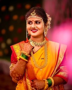 a woman dressed in an orange and yellow sari holding her hands to her chest