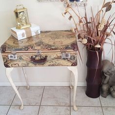 an old suitcase sitting on top of a table next to a vase with dried flowers