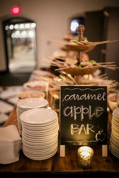 a table topped with plates and cups next to a chalkboard sign that says caramel apple bar