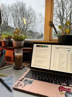 an open laptop computer sitting on top of a desk next to a cup of coffee