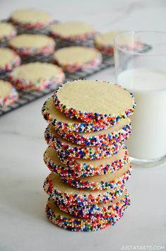 a stack of cookies with sprinkles next to a glass of milk on a table