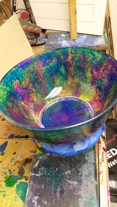 a colorful bowl sitting on top of a table next to paintbrushes and paper