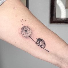 a woman's arm with a dandelion tattoo on it