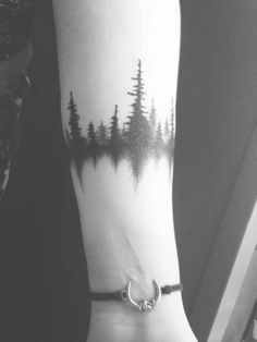 a person with a forest tattoo on their arm