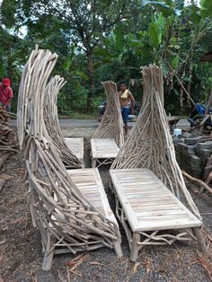 two wooden chairs made out of sticks on the ground next to some people sitting around