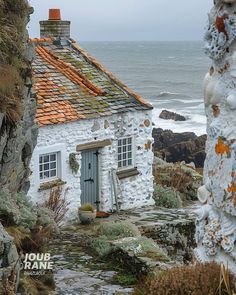 an old white house sitting on top of a rocky cliff next to the ocean with orange roof tiles