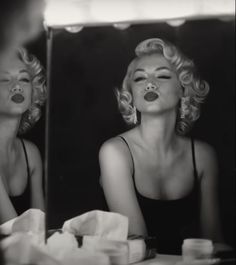 a black and white photo of a woman in front of a mirror with her mouth open