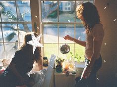 two women standing in front of a window with snowflakes on the windowsill