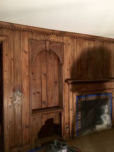 an empty room with wood paneling and a fireplace