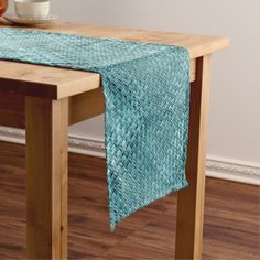 a wooden table with a blue and white table cloth on it, next to a bowl of fruit