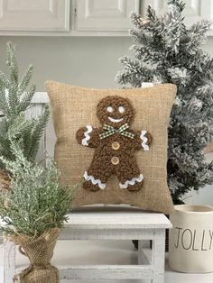 a pillow with a ginger on it sitting next to a potted plant and christmas tree