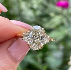 a close up of a person's hand holding an engagement ring