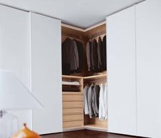 an open closet with clothes hanging on hangers and shoes sitting on the floor next to it