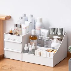 a white drawer with several bottles and containers on it next to a plant in a vase