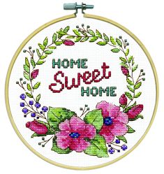 a cross stitch hoop with flowers and the words home sweet home on it's side