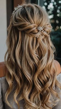 the back of a woman's head with long wavy hair and flowers in her hair