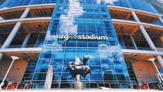 a large building that has a horse statue on the front and blue glass windows behind it