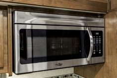 a stainless steel microwave oven in a kitchen with wooden cabinets and granite counter tops on the backsplash