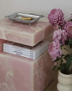 two pink marbled boxes are stacked on top of each other with flowers in the background