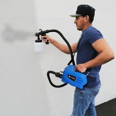 a man is using a sprayer to clean the wall with a blue canister