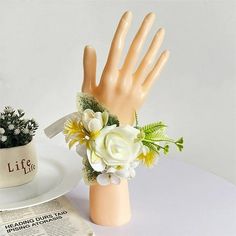 a fake hand with flowers on it next to a newspaper