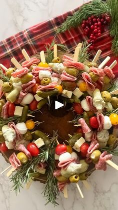 a wreath made out of meats and vegetables on skewers with pine needles