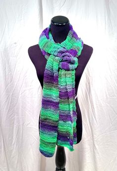 "This crochet scarf is sure to make you melt into it all winter long!  Made from 100% acrylic yarn in a funky striping mix of shades of green and purple, this scarf is long enough to keep you warm, even through the coldest winter!  The scarf measures approximately 89\" long and 9\" wide. This scarf can be worn in many different ways, and is sure to add flair to any fall outfit or winter coat.  A majority of the items you will find in my shop are one of a kind or one of a few. One of my favorite activities is to peruse the local yarn shops for anything that sparks my interest. This means that there will constantly be new and exciting items in my shop!" Green Acrylic Yarn Scarves For Winter, Green Acrylic Yarn Scarf For Winter, Green Acrylic Scarves For Winter, Green Yarn Scarves For Winter, Winter Green Yarn Scarves, Green Knitted Scarf For Winter, Green Winter Scarves One Size, One Size Purple Winter Scarves, Green Scarves For Winter