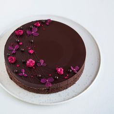 a chocolate cake decorated with pink flowers on a white plate