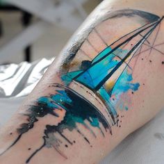 a person with a tattoo on their arm that has blue and black paint splatters all over it